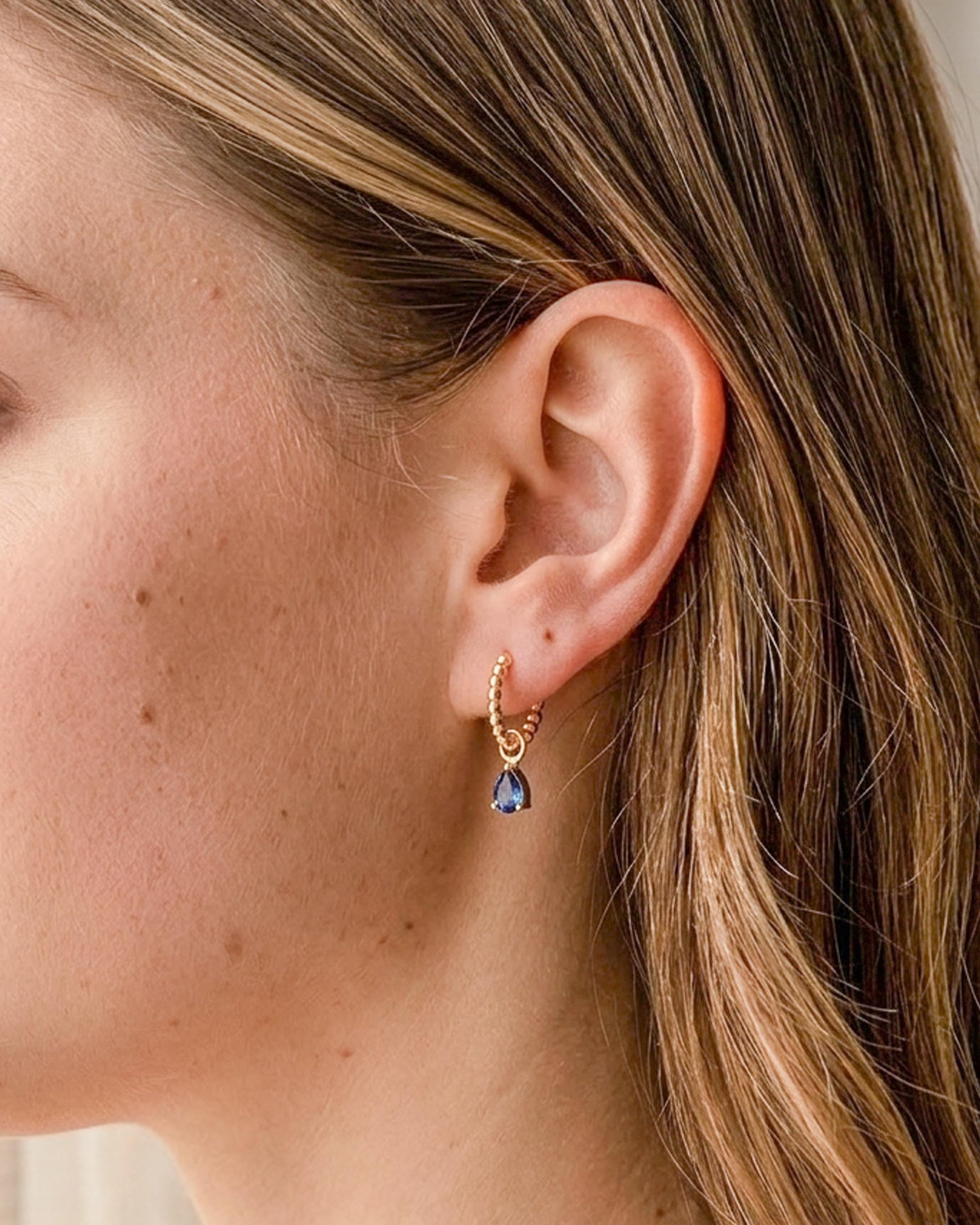 Model wearing 18K gold plated beaded hoop earrings with blue teardrop charm — HYFN