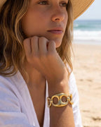Model wearing 18K gold plated chunky sculpted link cuff bracelet on beach — HYFN